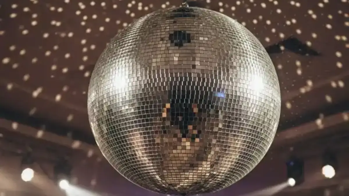 Bola disco grande iluminada sobre pista de fiesta nocturna