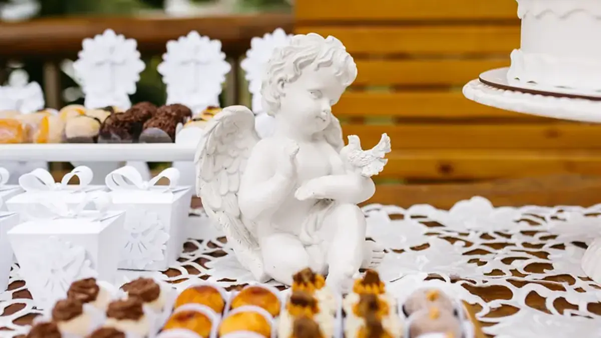 Mesa de dulces para bautizo con ángel blanco y postres