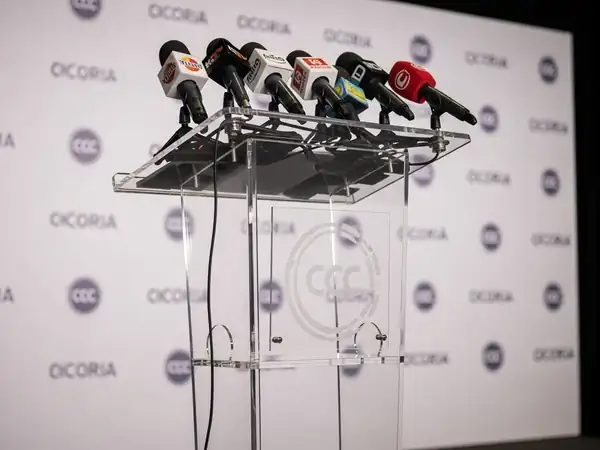 Atril para conferencias de acrílico con micrófonos en rueda de prensa