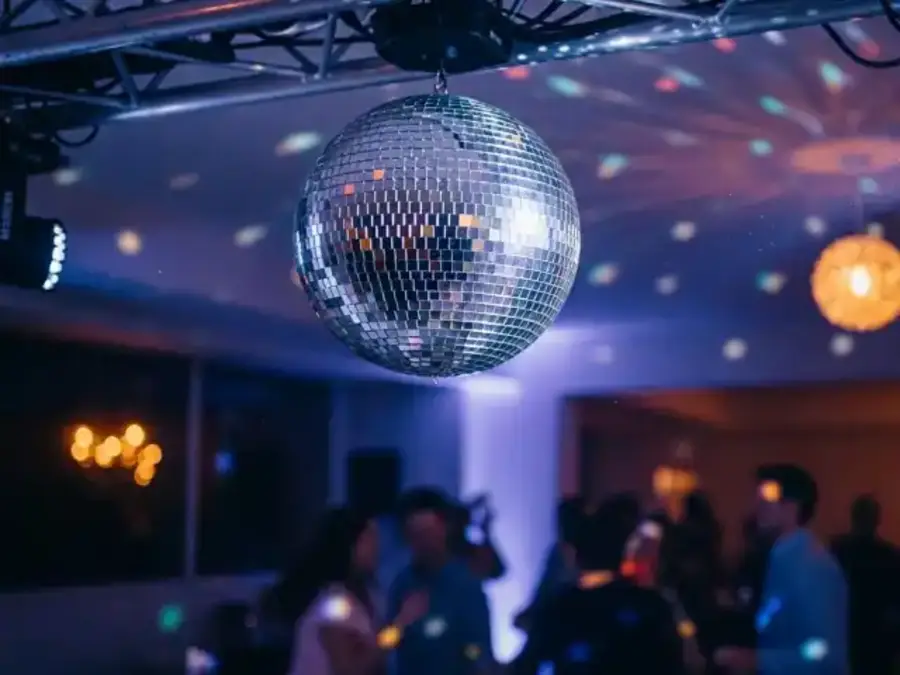 Bola de espejos suspendida sobre asistentes durante un evento nocturno