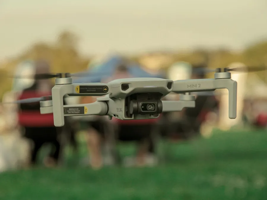 Dron compacto DJI en vuelo durante un evento al aire libre con invitados al fondo