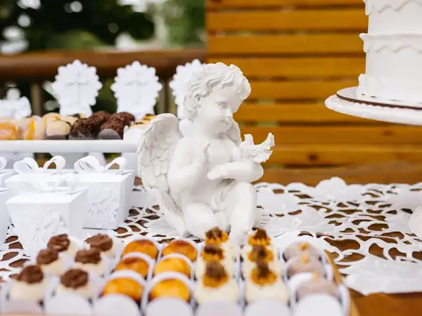 Mesa de dulces decorada para bautizo con postres y detalles blancos