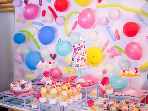 Mesa de dulces para fiesta infantil con globos de colores y cupcakes