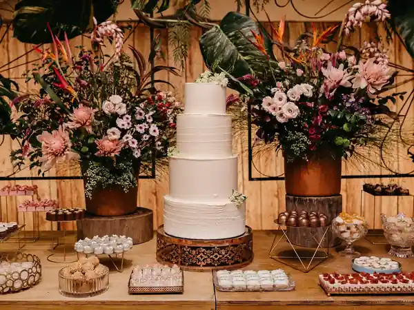 Mesa de postres para boda con pastel y arreglos florales