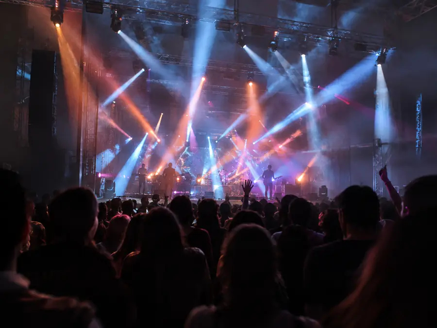 Escenario de concierto con cabezas móviles proyectando haces de colores