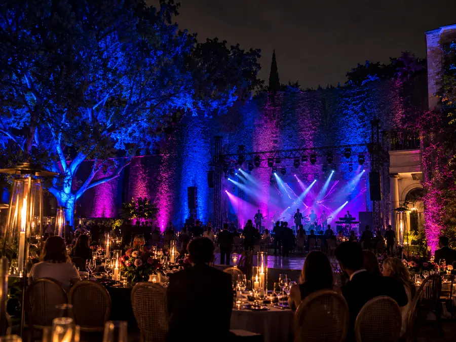 Muro y árboles de jardín iluminados con color azul y magenta