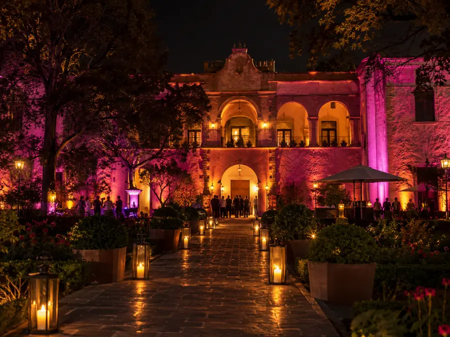 Fachada de salón bañada en luz magenta y ámbar